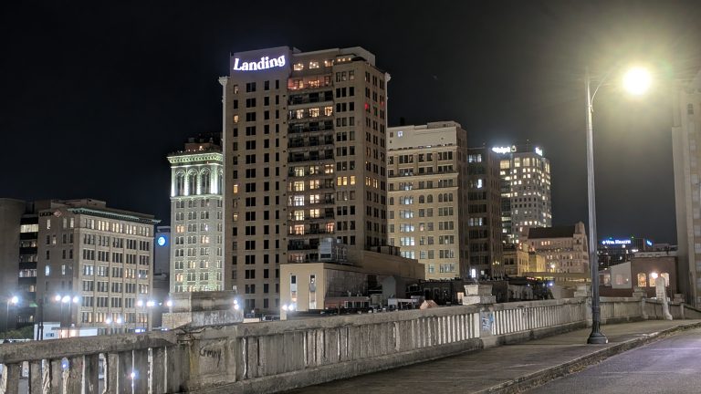 Several tall buildings and their lit signage as viewed from the Rainbow Bridge in downtown Birmingham, Ala.