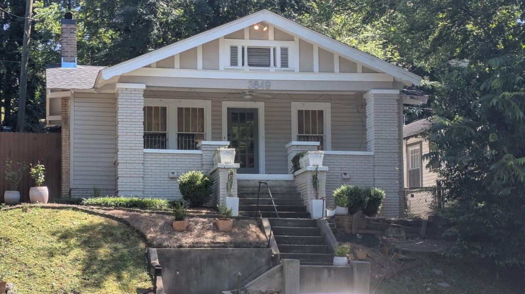 The front of a residential structure with concrete steps leading up to a painted brick facade.