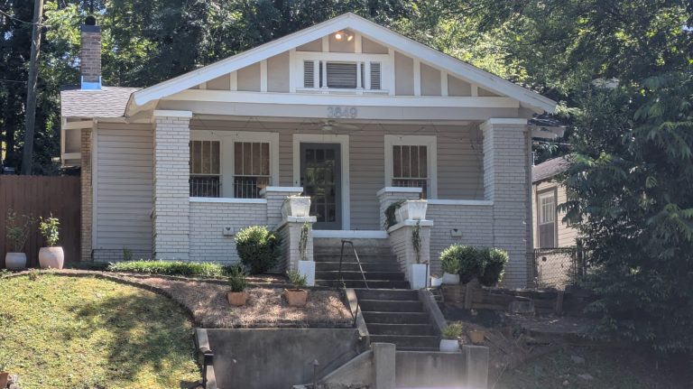 The front of a residential structure with concrete steps leading up to a painted brick facade.